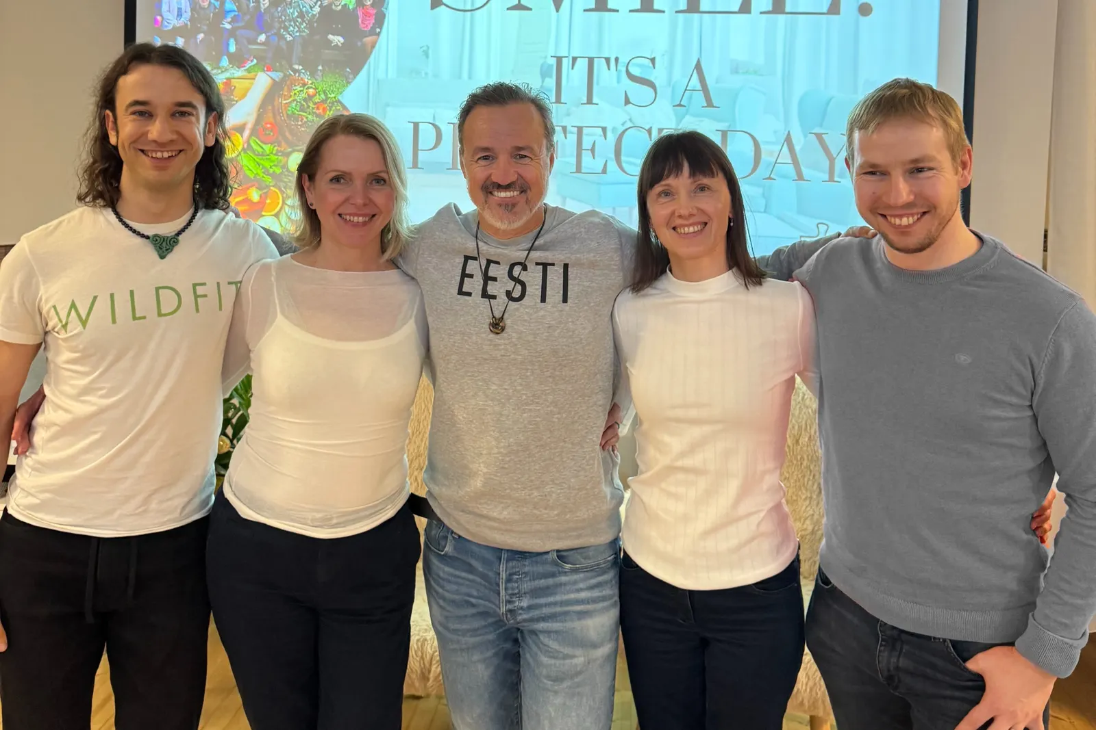 Joey Simsen in a WILDFIT t-shirt, arm in arm with WILDFIT creator Eric Edmeades and three others at a live event